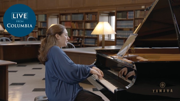 A woman in a blue shirt plays the piano.