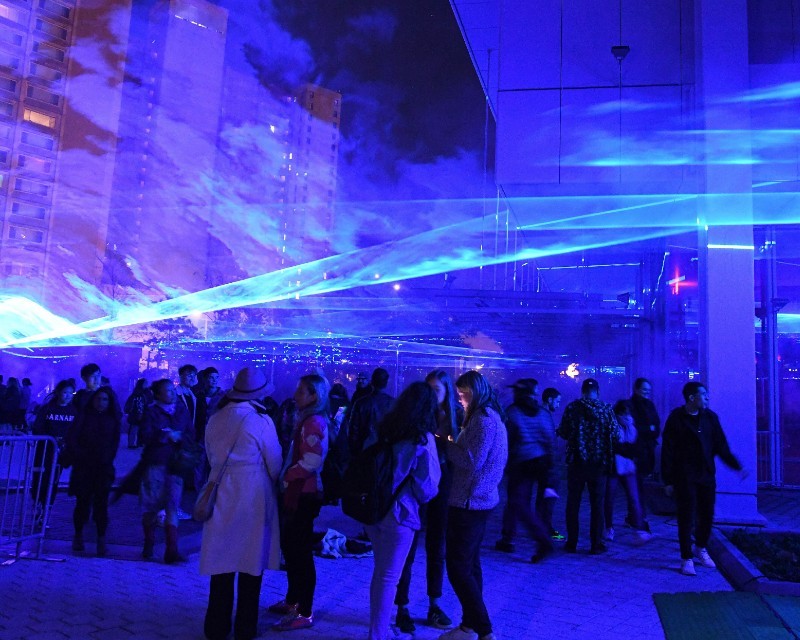 People walking under the LED light installation depicting sea water levels. 
