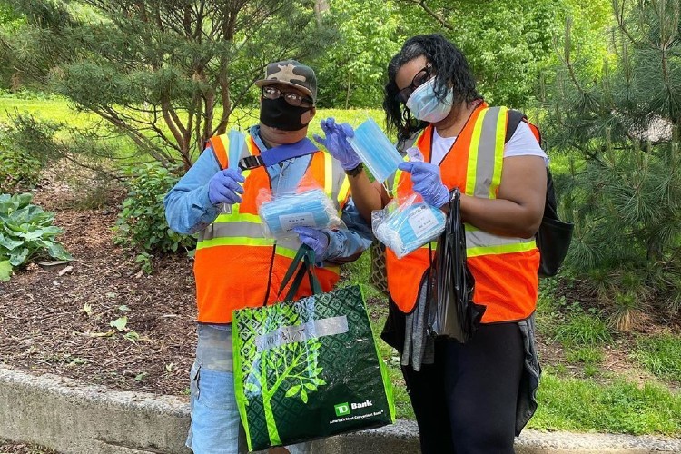 Two volunteers in orange vests with masks for distribution