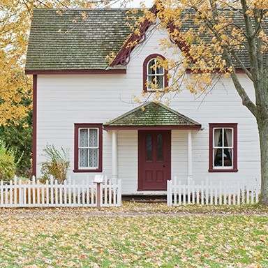 A white clapboard home with a red door and trim.