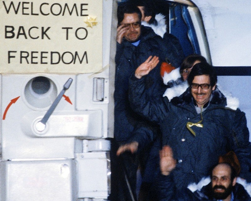 Hostages exiting plan with a sign that says welcome back to freedom. 