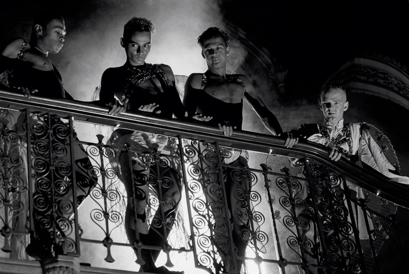 four men on in black and white photo standing on a balcony
