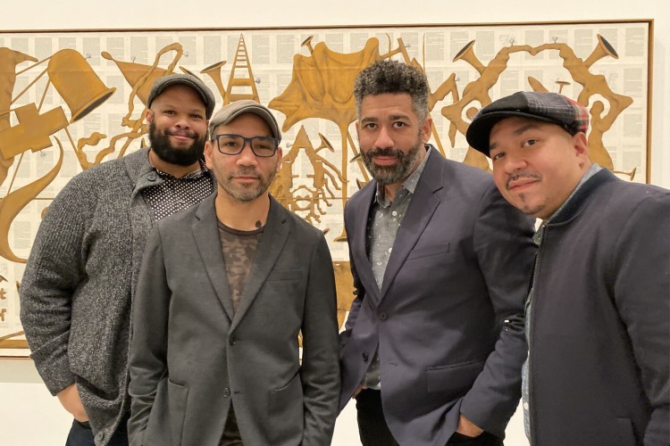 The four members of the Studio K.O.S. collective standing in front of a work of art.