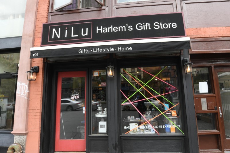 A black storefront with a sign saying "NiLu Harlem's Gift Store" and an awning that says "Gifts - Lifestyle - Home."