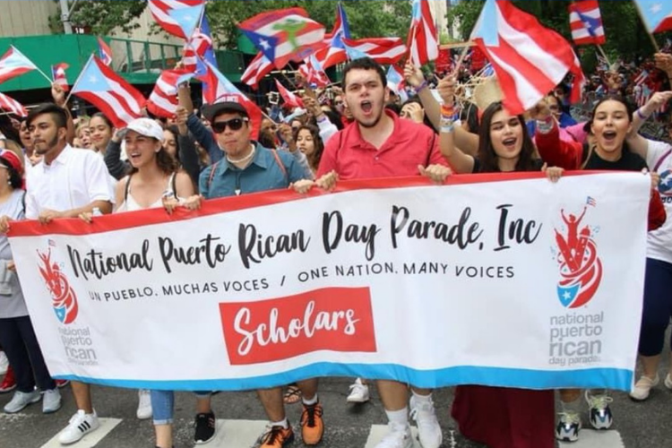 people at Puerto Rican day parade waving flag 