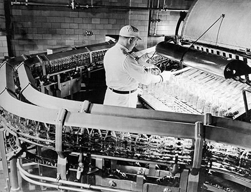 Worker in factory filling milk bottles.