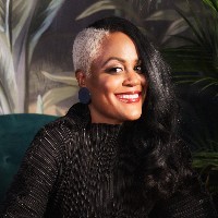 A woman in a black shirt with an undercut smiles at the camera.