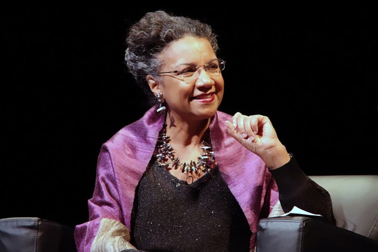 A'Lelia Bundles sitting down, wearing glasses and a purple scarf.