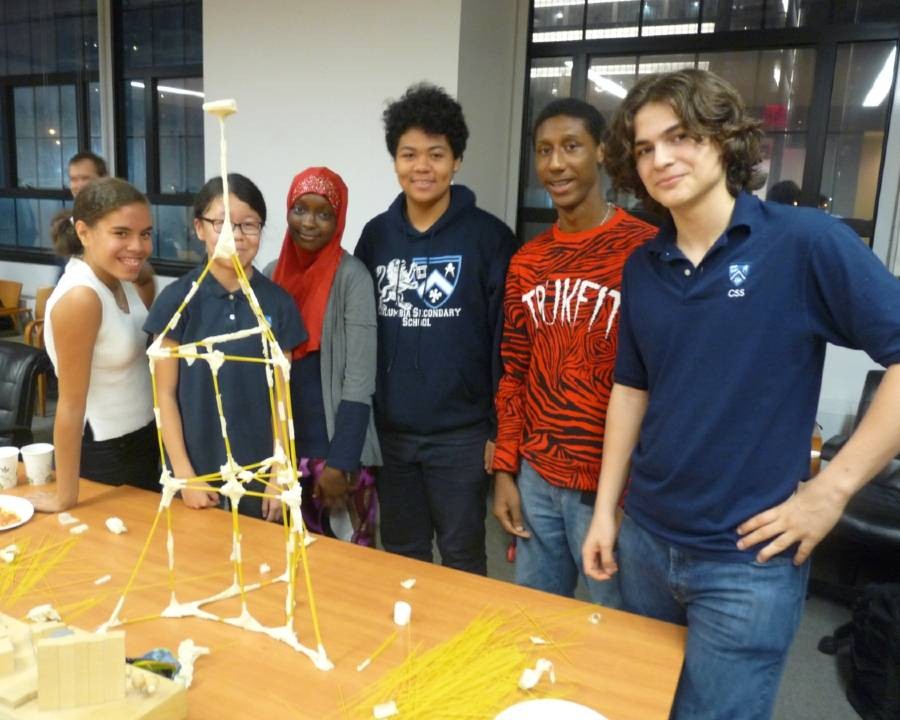 The six students from the winning team, standing behind their spaghetti and masking tape structure