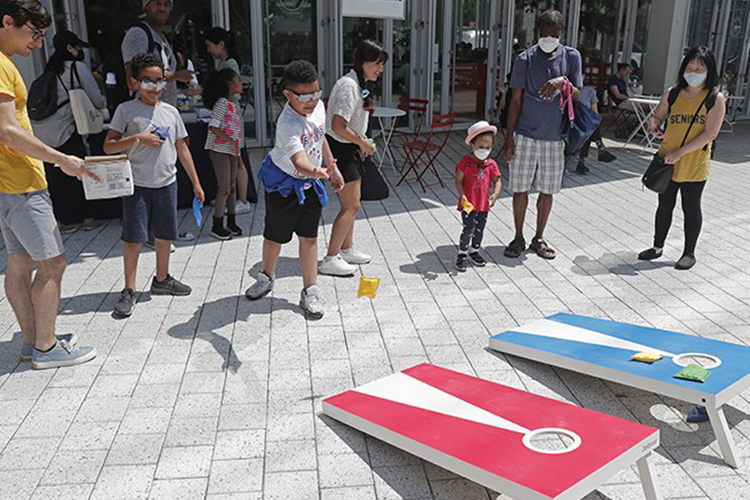 Children and adults play corn hole on the Manhattanville campus.