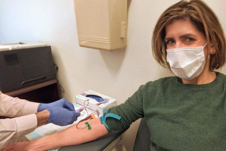 A woman in a surgical mask gets blood drawn.