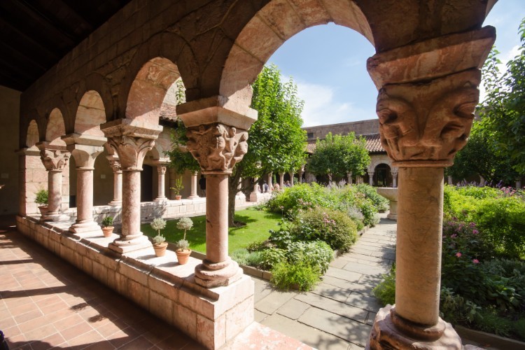 A view of a garden through a walkway with stone arches.
