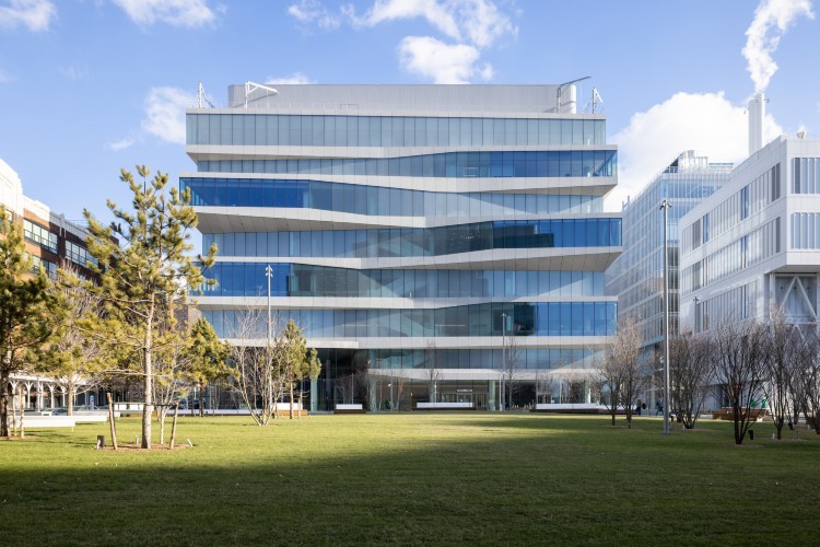 A building against a blue sky with a green lawn in front of it.