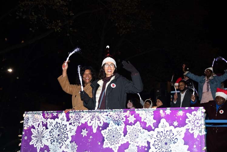 The Columbia-sponsored float in the Harlem Holiday Lights parade. Photo by Kevin Dale Photography. Two people wave at onlookers from the Purple snowflake-adorned Columbia float.