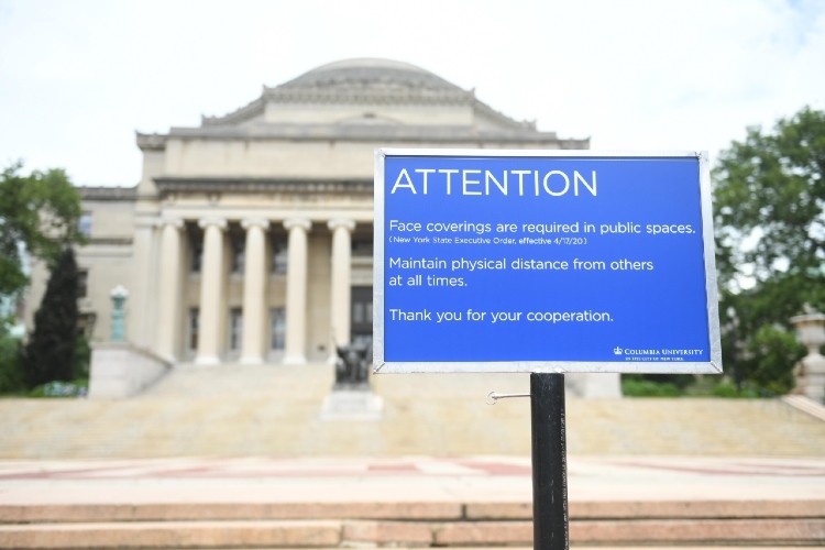 Blue sign on station in front of low memorial library using bokeh effect