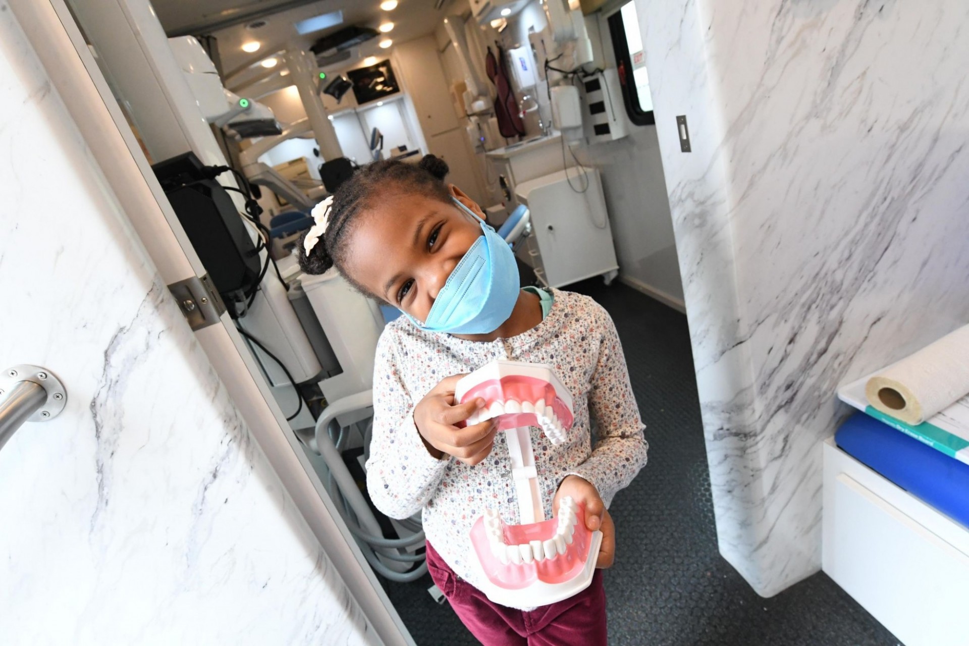 Photo by Eileen Barroso. A kid smiles with a tooth display in Columbia's dental van