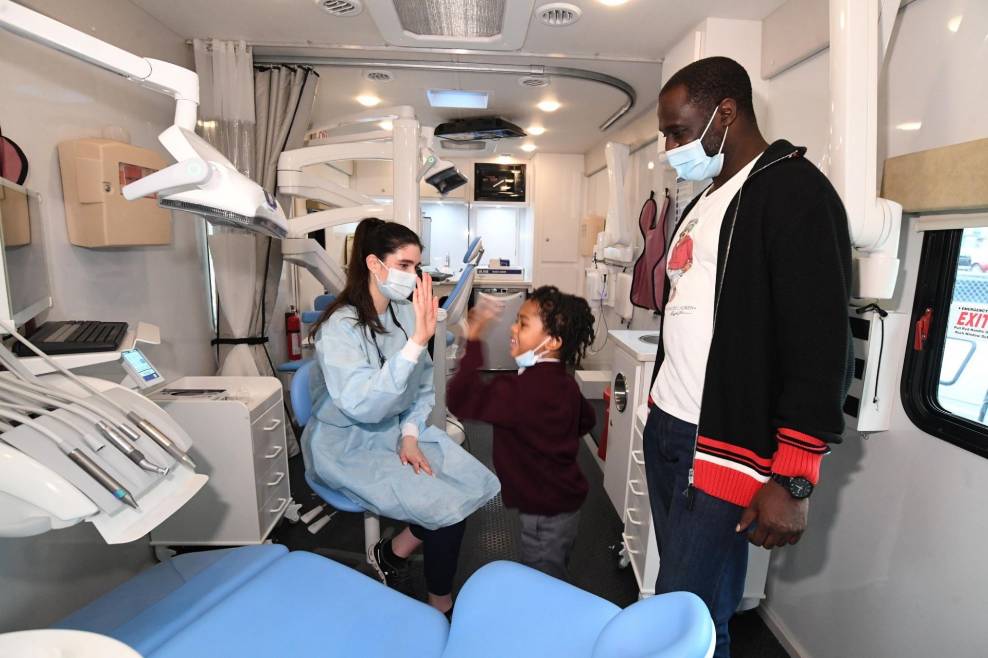 A father and son high five in the mobile dental van. 