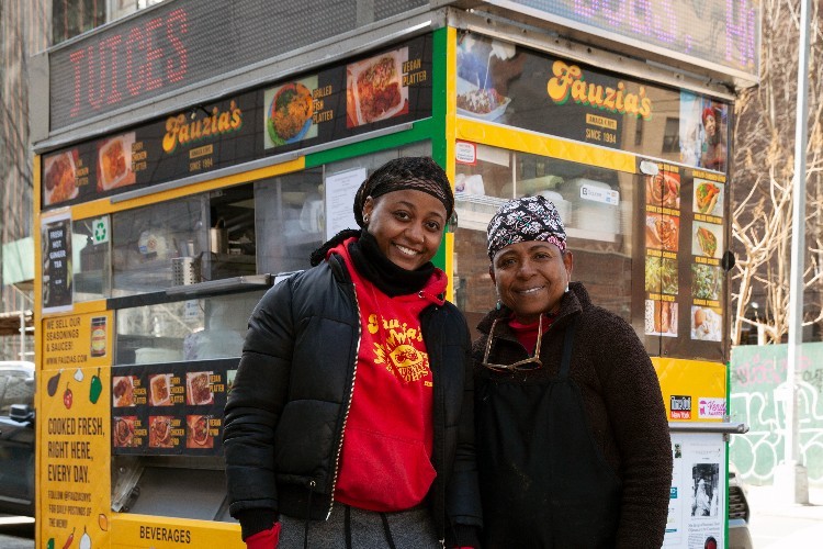 Two women standing in front a food cart