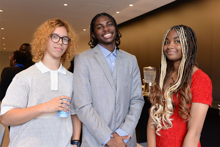 Three program graduates pose at a reception after their graduation. Photo by Leslye Smith. Three program graduates pose.