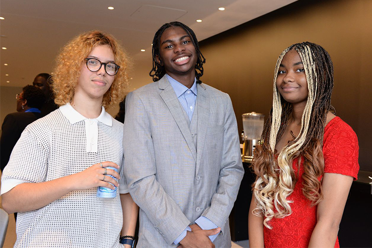 Three program graduates pose.