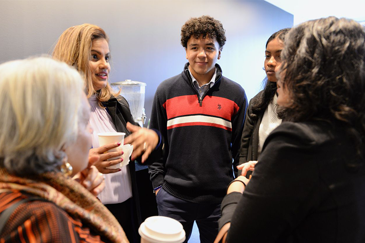 After the graduation, graduates, friends, and family joined a reception in David Geffen Hall. Photo by Leslye Smith. A circle of people talk in a reception hall.