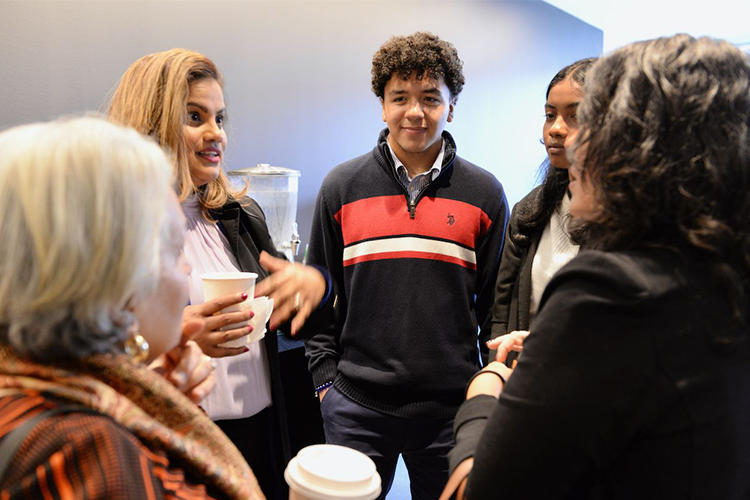 A circle of people talk in a reception hall. 