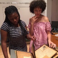 Two young women looking at a book in a museum.