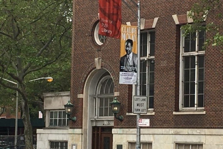 Street view image of banner featuring Claude McKay on lamp post in front of New York Public Library.