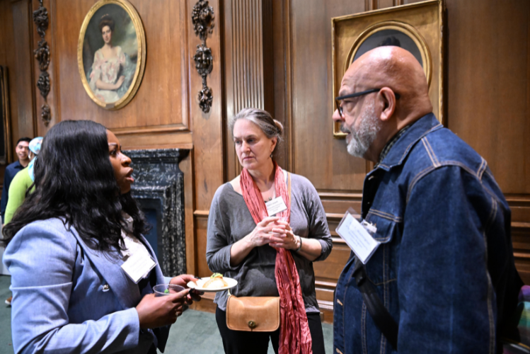 Phoebe-Sade Arnold, Director of Community Affairs at Columbia, speaks with Eric Washington, a Bundles Scholar from the second cohort, and Karen Jewett, former Vice President of Government & Community Affairs at Columbia. Photo by Eileen Barroso. Two women and a man talking, standing up in a circle.
