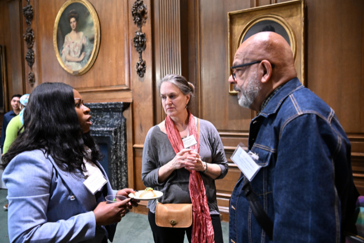 Two women and a man talking, standing up in a circle.