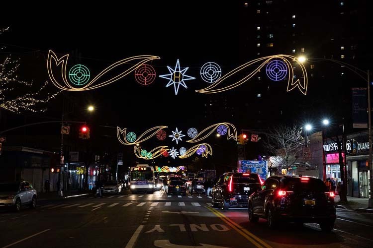 Festive lights hang across 125th Street in Harlem. Photo by Kevin Dale Photography. Holiday lights are strung across 125th Street in Harlem with cars moving underneath.