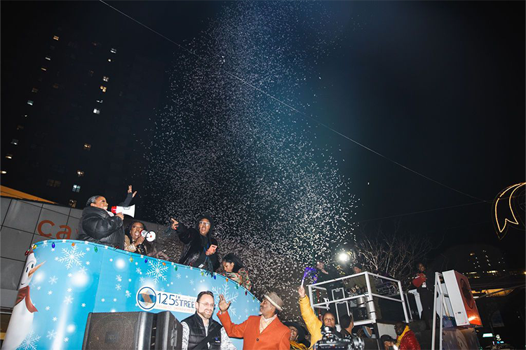 Grand Marshal Melba Wilson greets the crowd at the Harlem Holiday Lights Parade with confetti. 