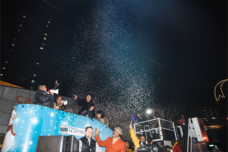 Grand Marshal Melba Wilson greets the crowd at the Harlem Holiday Lights Parade as confetti bursts in the air. Photo by Kevin Dale Photography. Grand Marshal Melba Wilson greets the crowd at the Harlem Holiday Lights Parade with confetti.
