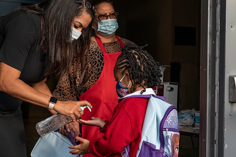 An adult pumps hand sanitizer into a child's hand.