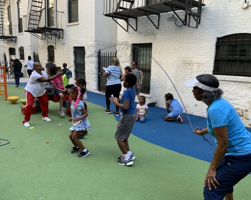 Harlem Wellness Center members and Youth Jumping Rope Adults and children jumping rope on playground