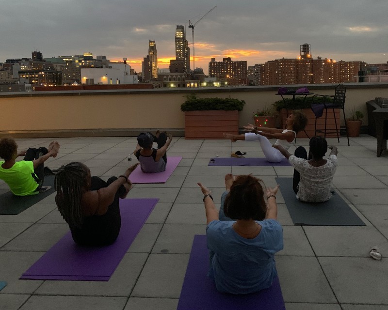 Yoga instructor guiding participants on a rooftop over looking the city