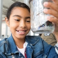 A girl looks at a jar.