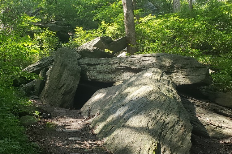 Large stones creating shadowed caves against a wooded background