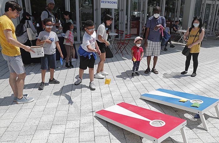 Children play bag toss in front of Dear Mama Coffee. Photo by Lou Rocco. Children play bag toss.