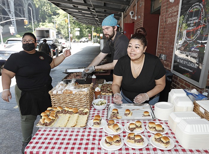 Employees at Dinosaur BBQ hand out food samples.