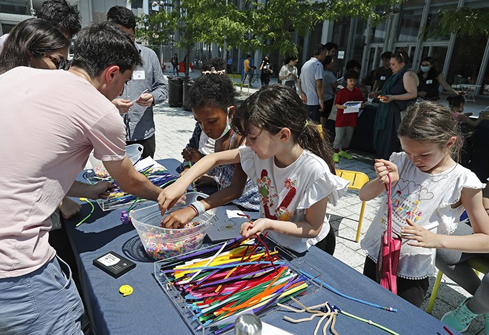 Children play with pipe cleaners on the Manhattanville Plaza.