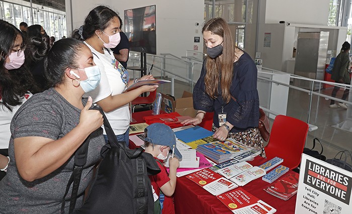 A New York Public Library staffer speaks with Manhattanville Community Day visitors. Photo by Lou Rocco. A NYPL volunteer hands out information about NYPL