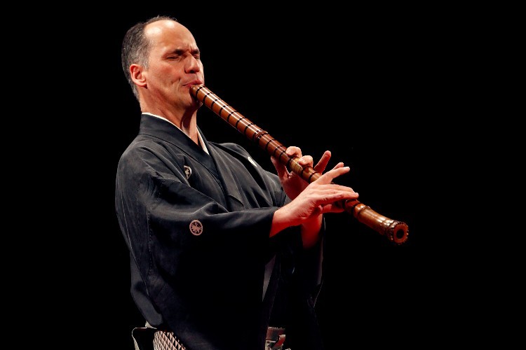 A man playing a wooden flute.