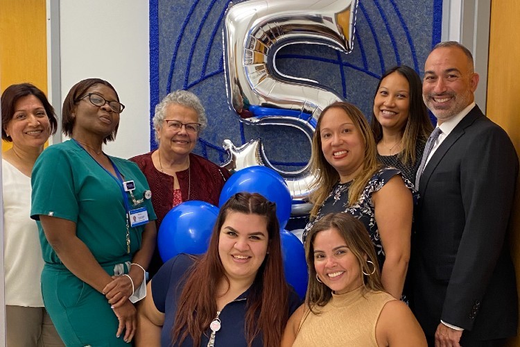 group photo in front of a balloon in the shape of the number 5