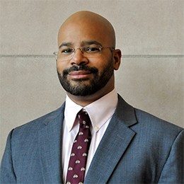 A man with glasses poses for a photo. 