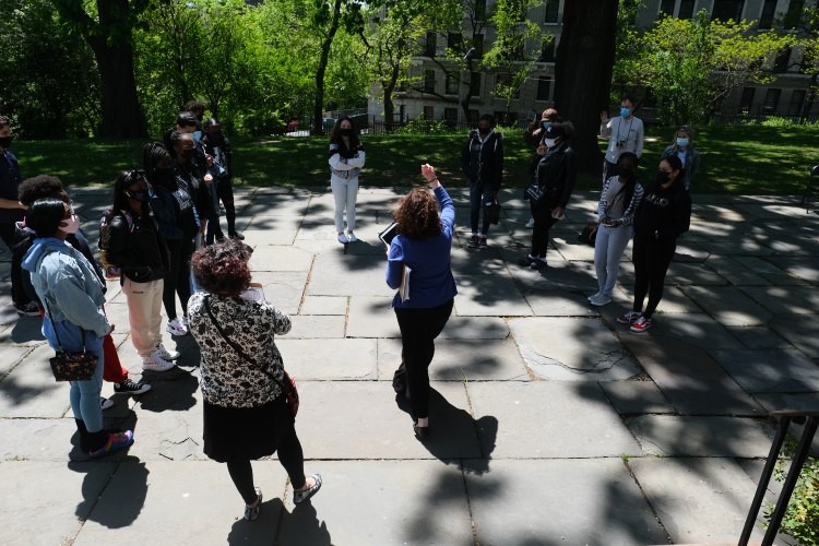 High school students standing in a circle looking an instructor who is gesturing to them.