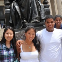 Three teenage students standing in front of the Alma Mater statue.