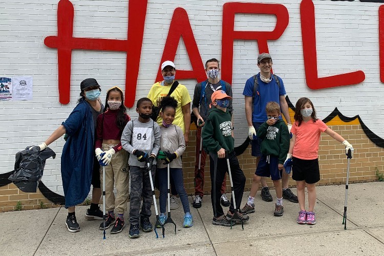 A group of adults and children holding trash grabbers.