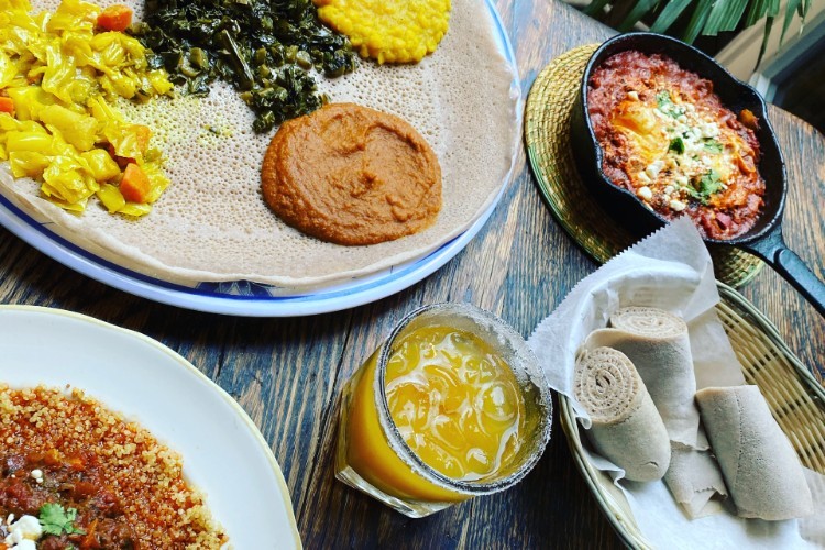 A variety of Ethiopian dishes and a cocktail glass with a drink in it.