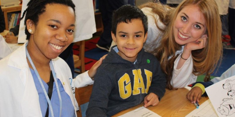A young child and two dentists at a community event